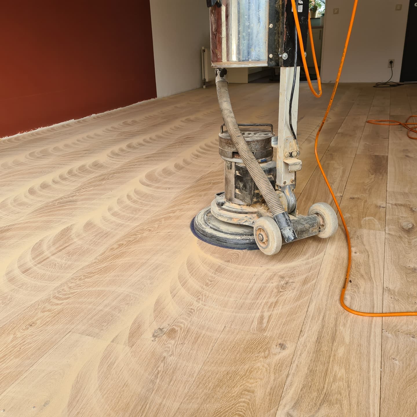 Schuurmachine aan het werk op een eiken vloer